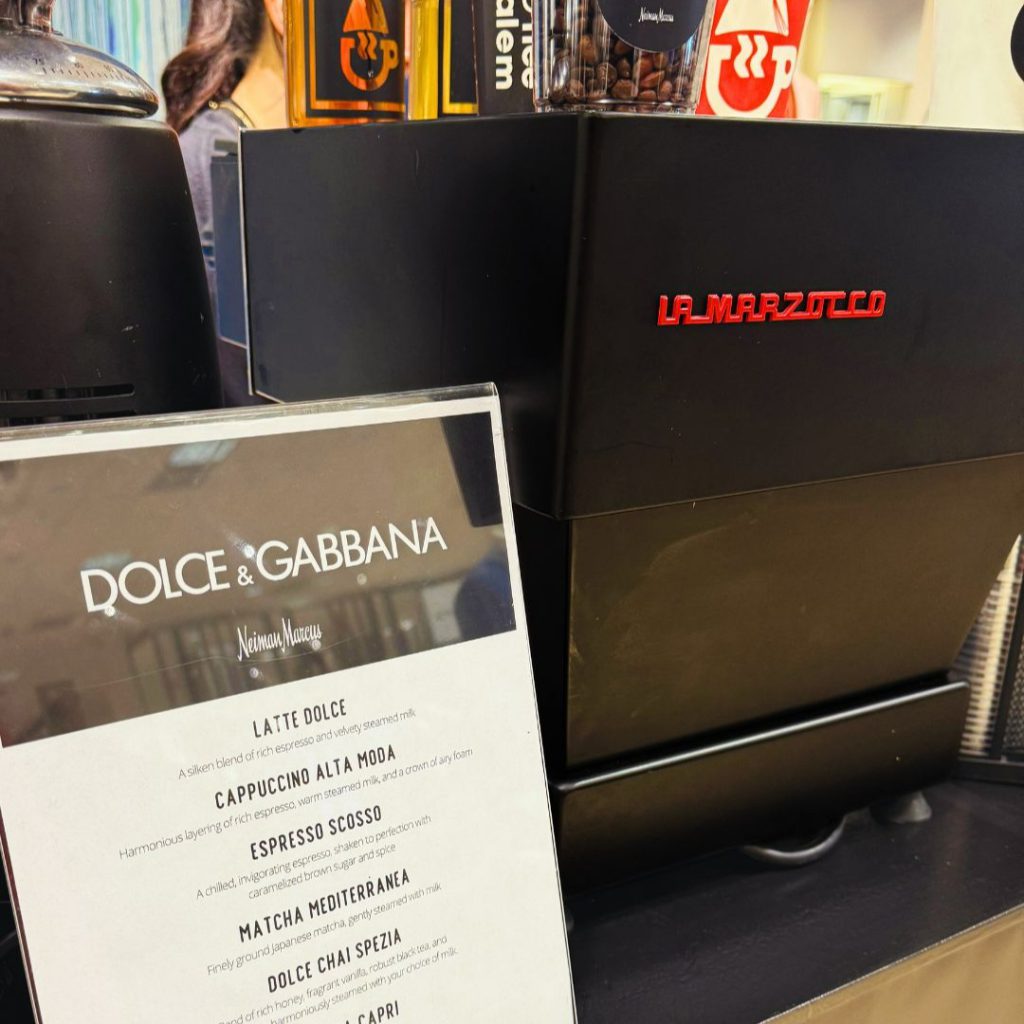 Dolce & Gabbana coffee menu beside a La Marzocco espresso machine at Neiman Marcus.